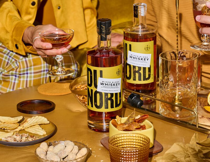 Du Nord Mixed Blood Whiskey is prominently displayed on a table filled with snacks.